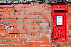 Red postbox mounted in a brick wall