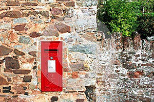 Red postbox in stone wall