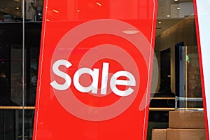 Red poster with word SALE on a glass store or shop window