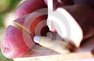 red potatoes and knife on wooden table