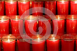 Red prayer candles burning inside a church