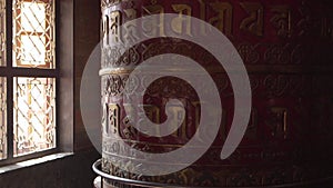 A red prayer wheel with the mantras