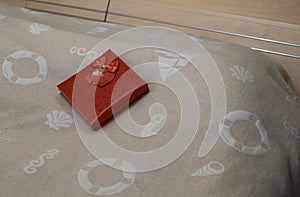 Red present box with heart shapes on the bed