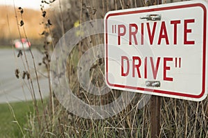 Red private drive sign with car passing in background