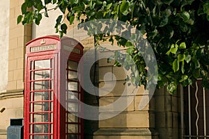 Red public phone box in front of a wall in Britain