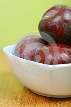 Red, purple plums in a bowl