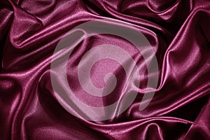 Red purple silk satin background. Shiny fabric with wavy soft pleats. Beautiful fabric background with empty space