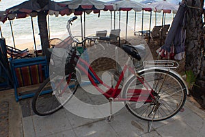 Red pushbike near beach umbrellas.