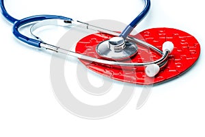 Red puzzle heart with stethoscope isolated on white background