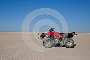 Red quad bike stands in desert