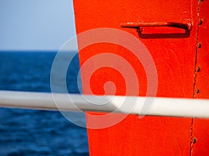Red railing steps on a ship - high contrast image - white handle bar in the foreground