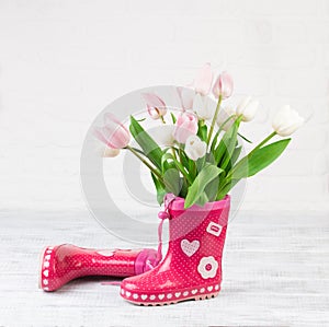 Red boots with tulips on wooden background