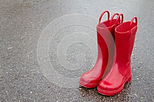 Red rain boots on wet pavement