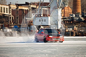 Red rally car drifting on ice of a frosen river