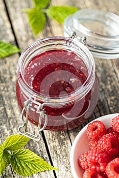 Red rasberries jam in jar and ripe raspberries