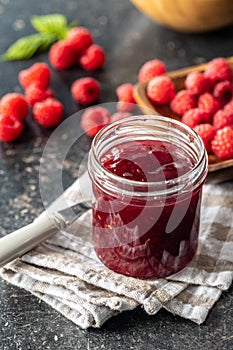 Red rasberries jam in jar and ripe raspberries