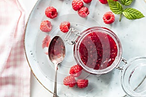 Red rasberries jam in jar and ripe raspberries