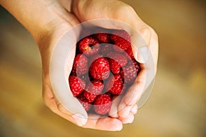 Red Raspberries on the child hands closeup. Raspberries in hands. Healthy, organic food and nutrition concept. eating, dieting,
