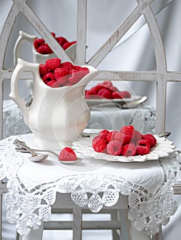 Red raspberries and white lace in a shabby chic background.