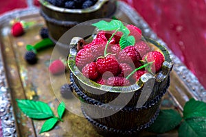 Red raspberry with leaf in a basket on vintage metal tray. Close up.