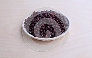 Red raw beans clean for cooking in a white saucer on the table side view