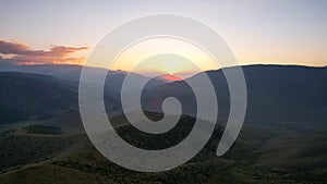 Red rays of the sun at sunset among the mountains