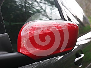 Red rear view side mirror reflecting the trees