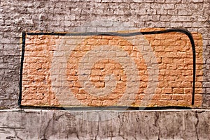 Red rectangular graffiti with black edging on a brown brick wall in Russia