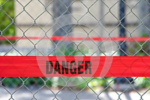 Red reflective danger barrier tape across a chain link fence