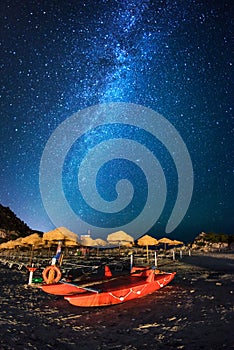 Red rescue catamaran on the beach by night under the milky way