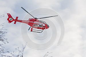 Red rescue helicopter fly in snowy mountains