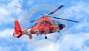 Red rescue helicopter moving in blue sky