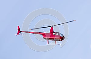 Red rescue helicopter moving in blue sky