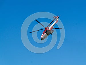 Red rescue helicopter moving in blue sky. Rapid medical assistance or rescue by helicopter