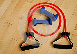 Red Resistance Band and Blue Weights on Gym Floor