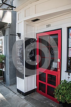 Red restaurant door with a closed sign in the window. There are two chalk boards advertising baked goods