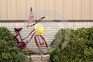 Red retro bicycle leaning against outside wall of fire department as decor.