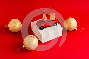 Red retro car with a gift box on the roof on a white podium and a red background with a new-fashion ball. a copy of the space