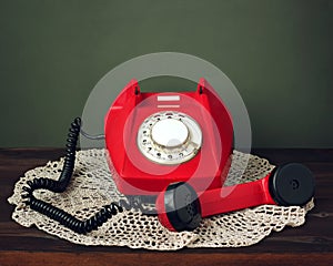 Red retro rotary phone on a lacy napkin.