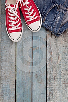 Red retro sneakers and jeans on a blue wooden background