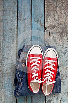 Red retro sneakers and jeans on a blue wooden background