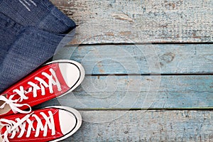 Red retro sneakers and jeans on a blue wooden background