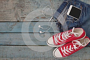 Red retro sneakers and smartphone with headset-earphones in a po