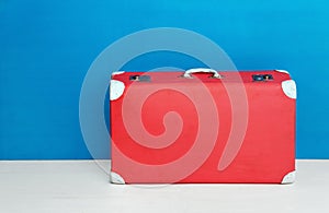 Red retro suitcase at the blue wall. Travel and adventure