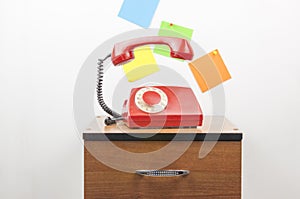 Red retro telephone on wooden nightstand