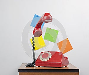 Red retro telephone on wooden nightstand