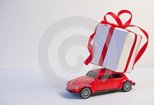 Red retro toy car delivering Christmas or New Year gifts on the roof on a white background.