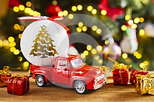 Red retro toy truck with Christmas ball and gift boxes on wooden table