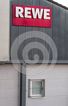 Red REWE label outside on a gray building