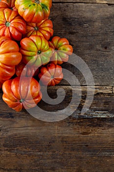 Red ribbed tomatoes on a wooden background. American or Florentine variety Nina. Food on the table top view. Autumn